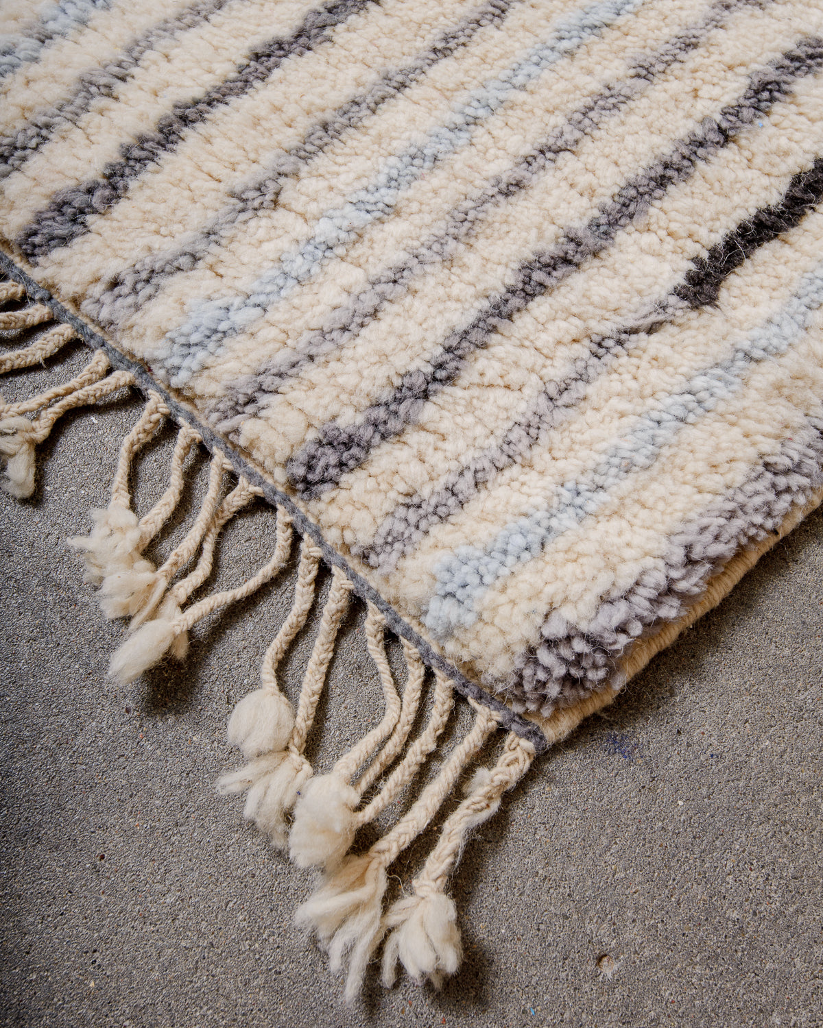Corner of rug made of thick wool pile and natural wool tassels.
